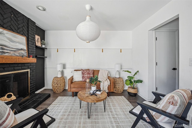 living room with a brick fireplace and dark wood-type flooring