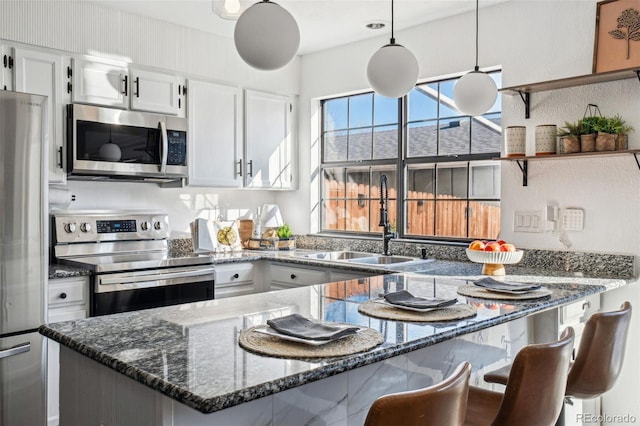 kitchen featuring sink, decorative light fixtures, stainless steel appliances, and white cabinets