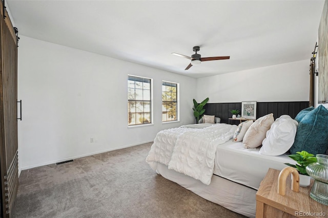 carpeted bedroom featuring ceiling fan and a barn door