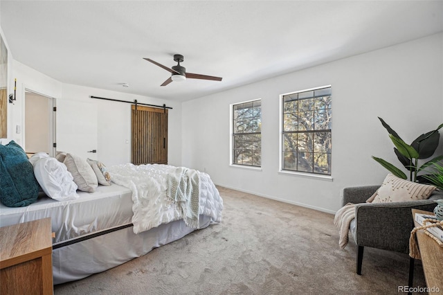 carpeted bedroom featuring ceiling fan and a barn door