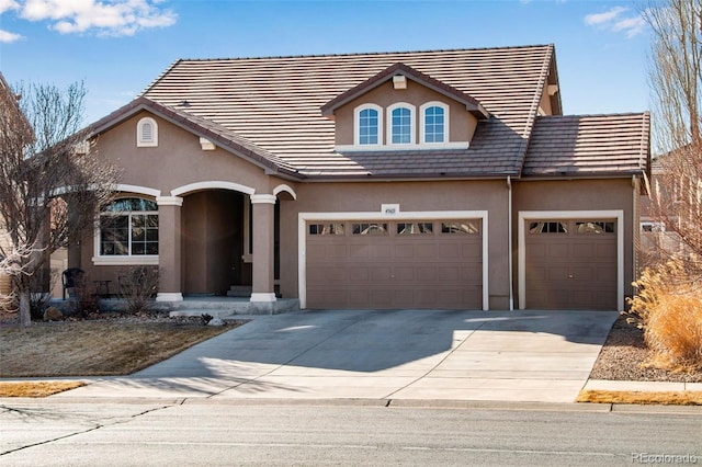 view of front facade with a garage, driveway, and stucco siding