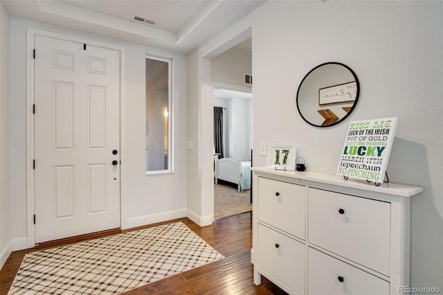 foyer with baseboards, visible vents, and dark wood-type flooring