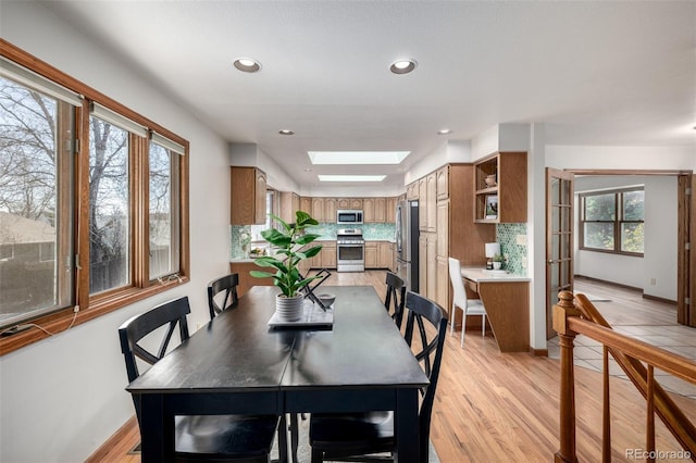 dining area featuring baseboards, recessed lighting, a skylight, and light wood-style floors