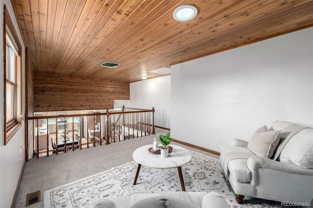 living area with visible vents, baseboards, carpet, an upstairs landing, and wooden ceiling