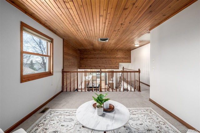 hallway with visible vents, an upstairs landing, carpet, wooden ceiling, and baseboards