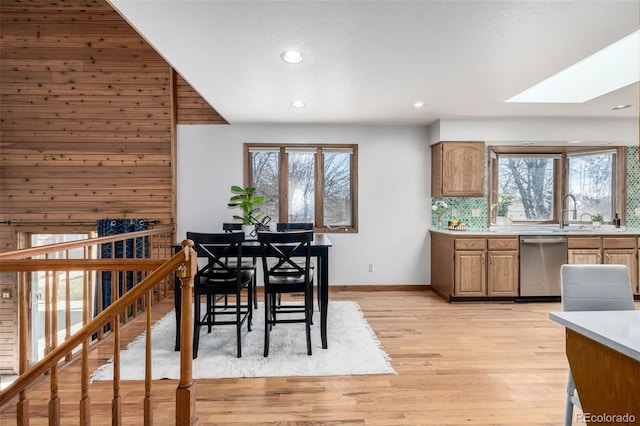 dining space featuring light wood finished floors, recessed lighting, a skylight, and baseboards