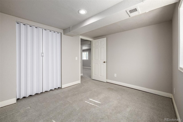 unfurnished bedroom with carpet flooring, baseboards, visible vents, and a textured ceiling