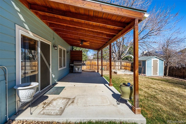 view of patio with an outdoor structure, a storage unit, a fenced backyard, and ceiling fan