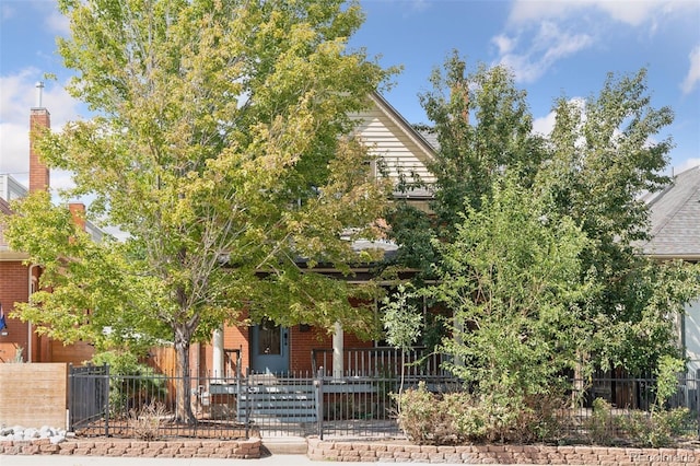 view of property hidden behind natural elements featuring a porch