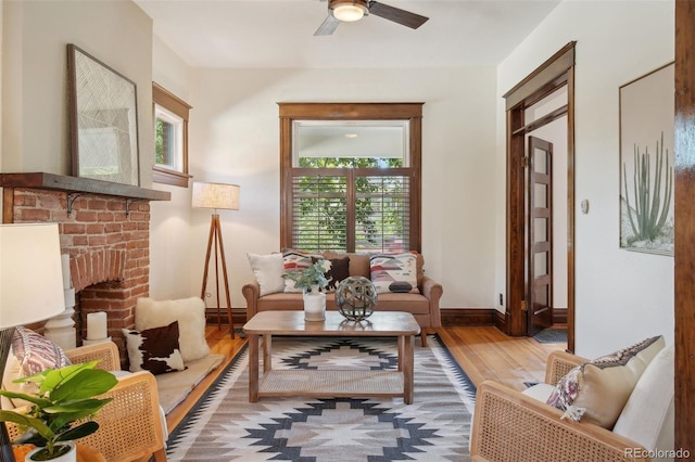 living area featuring ceiling fan, wood-type flooring, a fireplace, and a wealth of natural light