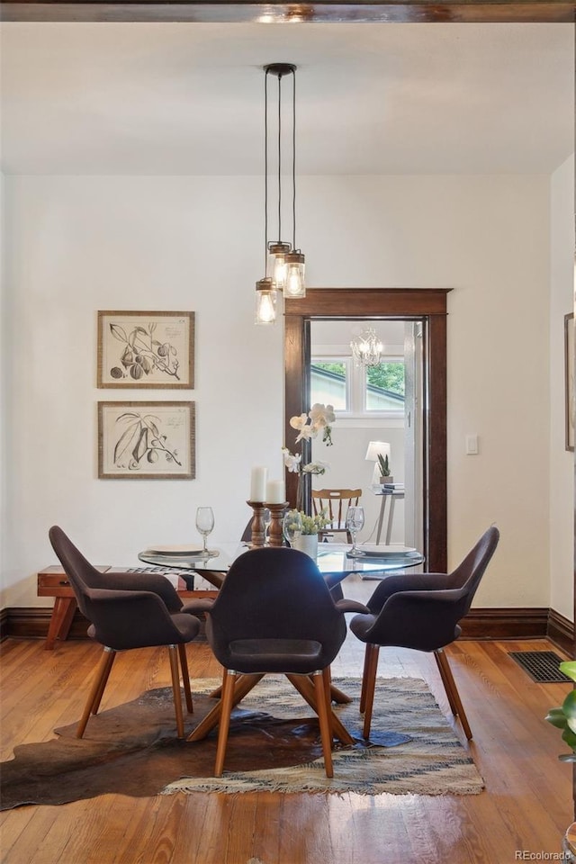 dining area with wood-type flooring and a chandelier