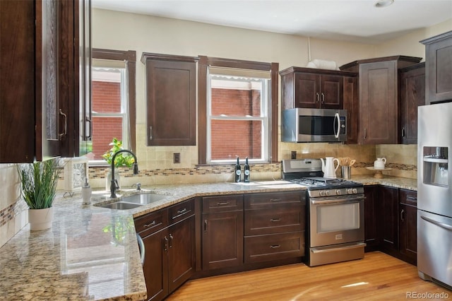 kitchen with light stone counters, sink, dark brown cabinetry, and stainless steel appliances