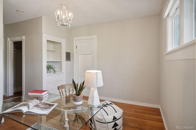 dining space featuring built in features, wood-type flooring, and an inviting chandelier