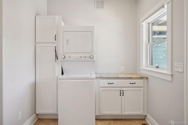 washroom with cabinets and stacked washer and dryer