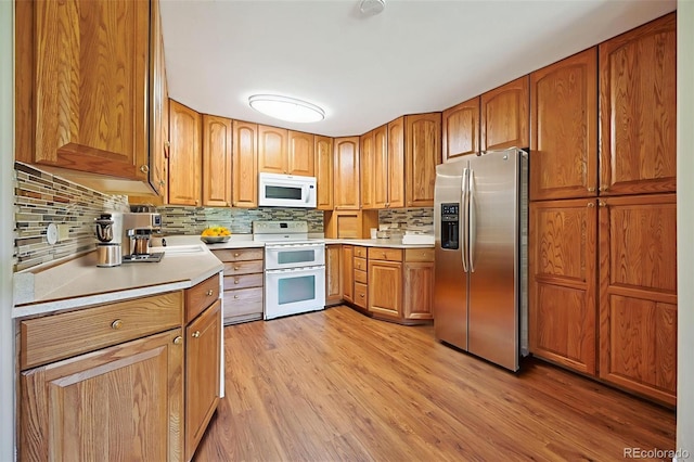 740 S Alton Way Unit 2A, Denver, CO 80247 - kitchen with white appliances, decorative backsplash, light countertops, light wood-style floors, and brown cabinets
