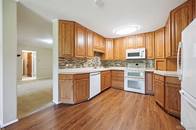 740 S Alton Way Unit 2A, Denver, CO 80247 - kitchen with white appliances, wood finished floors, backsplash, light countertops, and brown cabinets