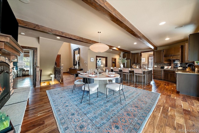 8090 S Homesteader Dr, Morrison, CO 80465 - dining space with a warm lit fireplace, beamed ceiling, dark wood-type flooring, and recessed lighting