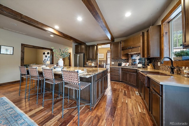 8090 S Homesteader Dr, Morrison, CO 80465 - kitchen featuring beam ceiling, dark wood-style floors, a center island, decorative backsplash, and a breakfast bar area