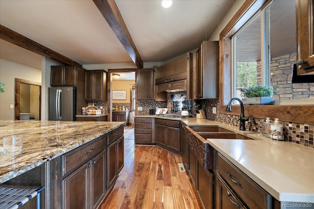 8090 S Homesteader Dr, Morrison, CO 80465 - kitchen featuring appliances with stainless steel finishes, beamed ceiling, light wood-style floors, backsplash, and dark brown cabinets