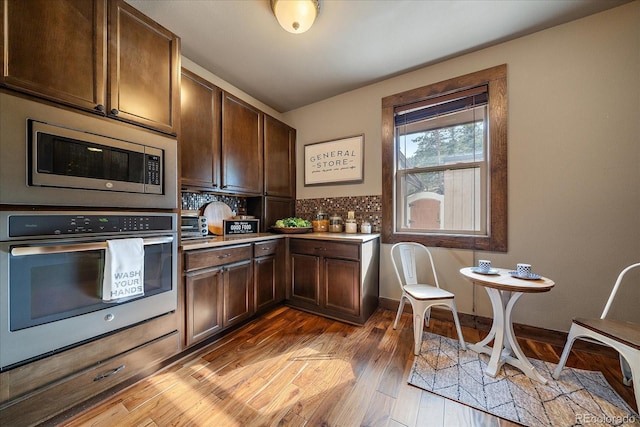 8090 S Homesteader Dr, Morrison, CO 80465 - kitchen with appliances with stainless steel finishes, light wood-style floors, dark brown cabinets, tasteful backsplash, and light countertops
