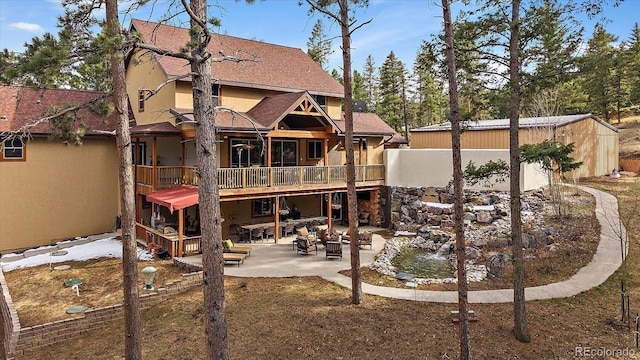 8090 S Homesteader Dr, Morrison, CO 80465 - rear view of property with a patio, stucco siding, a wooden deck, and a shingled roof