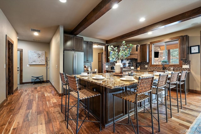 8090 S Homesteader Dr, Morrison, CO 80465 - kitchen with beam ceiling, light wood finished floors, decorative backsplash, dark brown cabinetry, and light stone countertops