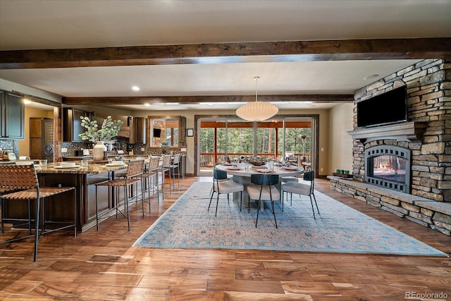 8090 S Homesteader Dr, Morrison, CO 80465 - dining area featuring beam ceiling, a stone fireplace, and wood finished floors