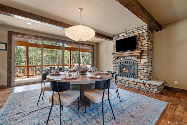 8090 S Homesteader Dr, Morrison, CO 80465 - dining room with beam ceiling, a stone fireplace, and wood finished floors