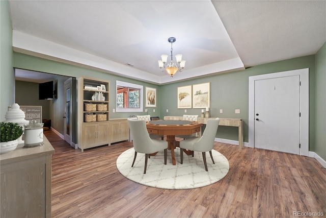 8090 S Homesteader Dr, Morrison, CO 80465 - dining room featuring a chandelier, wood finished floors, and a raised ceiling