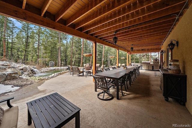 8090 S Homesteader Dr, Morrison, CO 80465 - view of patio featuring an outdoor kitchen, outdoor dining space, and a wooded view