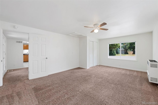 carpeted empty room with radiator, heating unit, and ceiling fan