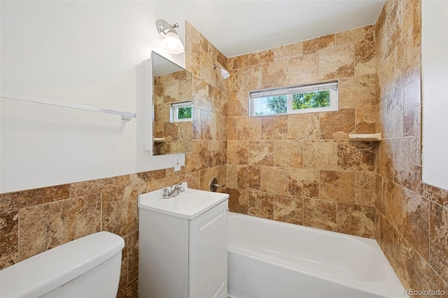 full bathroom with tile walls, toilet, tiled shower / bath combo, and vanity