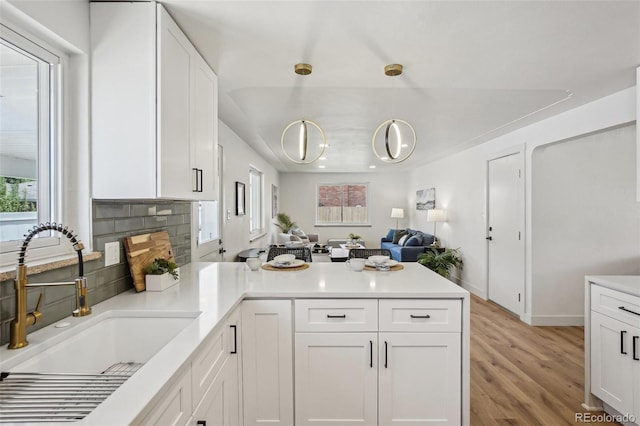6068 Lee St, Arvada, CO 80004 - kitchen featuring a sink, a peninsula, white cabinetry, and light wood-style flooring