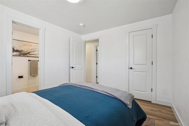6068 Lee St, Arvada, CO 80004 - bedroom with wood finished floors, baseboards, and connected bathroom
