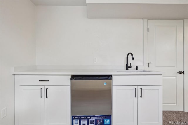 6068 Lee St, Arvada, CO 80004 - kitchen with dishwashing machine, a sink, light countertops, and white cabinetry