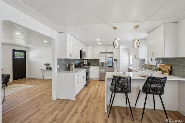 6068 Lee St, Arvada, CO 80004 - kitchen with appliances with stainless steel finishes, a sink, light countertops, a peninsula, and recessed lighting