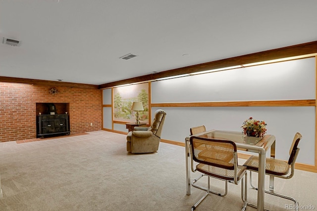 carpeted dining area with a brick fireplace and brick wall