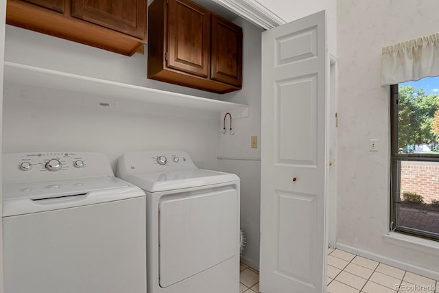 laundry room with washing machine and clothes dryer, a healthy amount of sunlight, light tile patterned floors, and cabinets