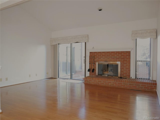 unfurnished living room with a fireplace, wood-type flooring, and lofted ceiling