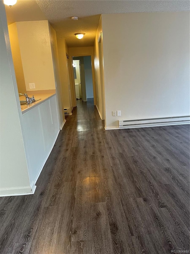 hall with sink, a baseboard radiator, dark hardwood / wood-style flooring, and a textured ceiling