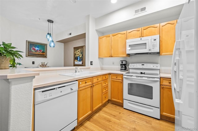 kitchen featuring sink, kitchen peninsula, pendant lighting, white appliances, and light wood-type flooring