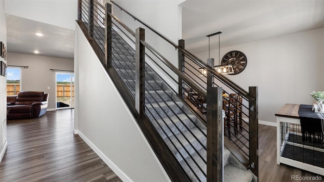 staircase featuring hardwood / wood-style flooring and an inviting chandelier