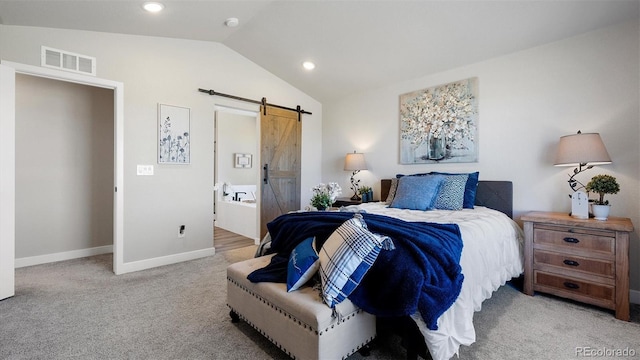 bedroom featuring ensuite bathroom, a barn door, lofted ceiling, and light carpet