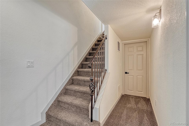 staircase with carpet and a textured ceiling