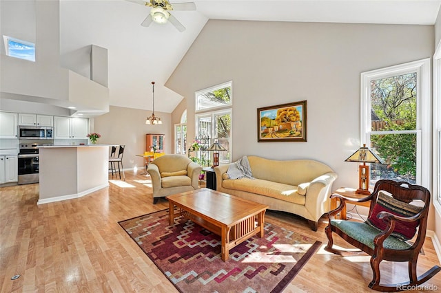 2252 S Yosemite Cir, Denver, CO 80231 - living room with high vaulted ceiling, baseboards, light wood finished floors, and ceiling fan with notable chandelier