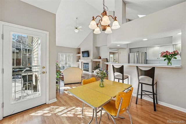 2252 S Yosemite Cir, Denver, CO 80231 - dining room featuring high vaulted ceiling, baseboards, light wood finished floors, and ceiling fan with notable chandelier