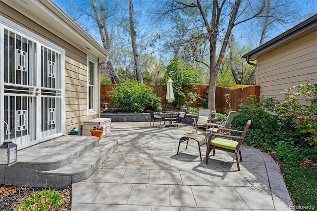 view of patio with a fenced backyard, outdoor dining space, and french doors