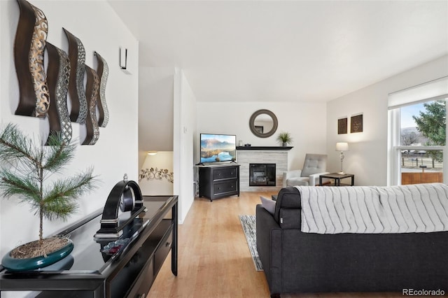 living area with light wood-type flooring and a glass covered fireplace