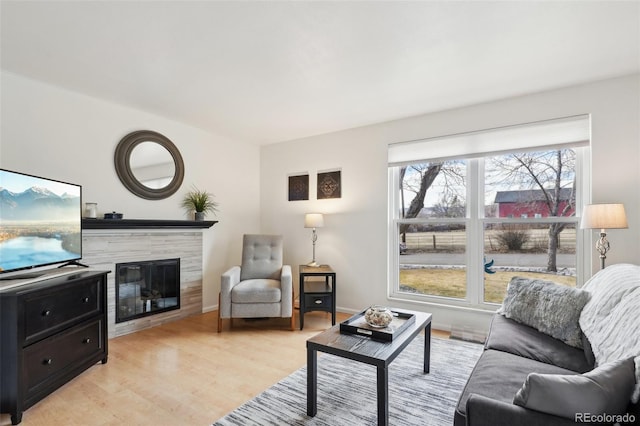 living area featuring light wood finished floors, baseboards, and a tiled fireplace