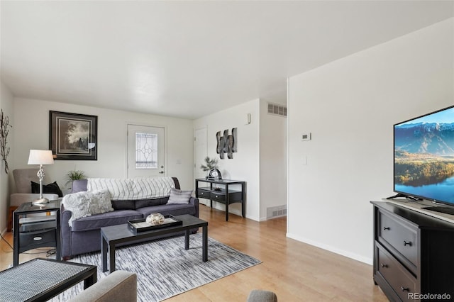 living area with light wood finished floors, visible vents, and baseboards